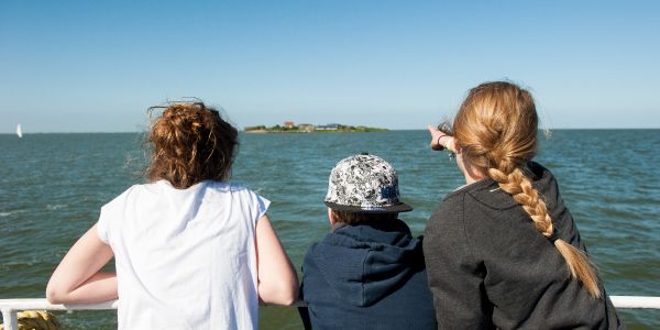 kinderen wijzen naar fort pampus vanaf boot