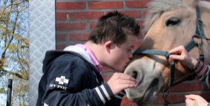 gehandicapt kind geeft pony een kus op snuit