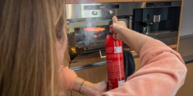 vrouw blust brand in de oven met brandblusser
