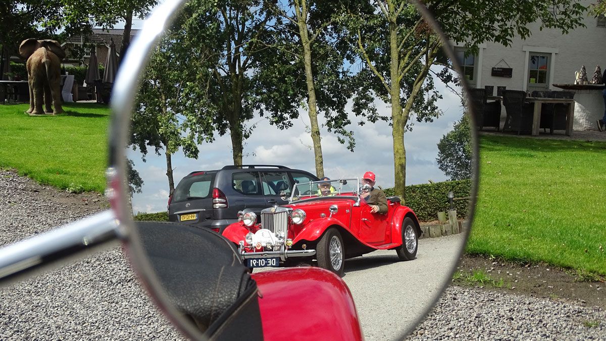 man in oldtimer maakt foto van buitenspiegel