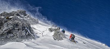 persoon loopt berg op in de sneeuw richting de top