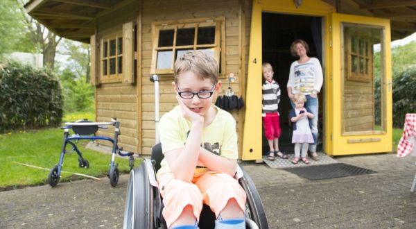 Jongetje in rolstoel kijkt in camera