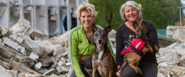 vrouwen met zoekhonden bij puin