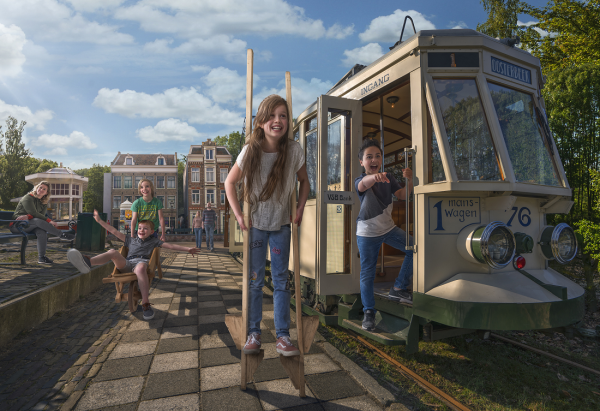 meisje op stelten in openluchtmuseum bij een tram