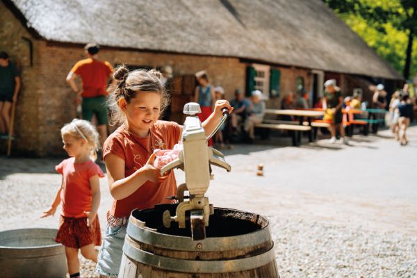 kinderen aan waterpomp in vernieuwd kindererf openluchtmuseum