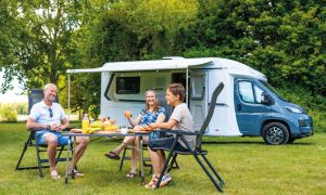 persoon zit voor verzekerde camper op de camping