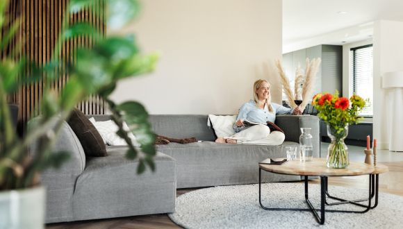 vrouw op bank met inboedelverzekering leest magazine