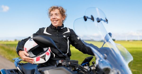 Vrouw met helm in haar hand op een stilstaande motor