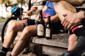 wielrenners drinken speciaalbier op een bankje buiten