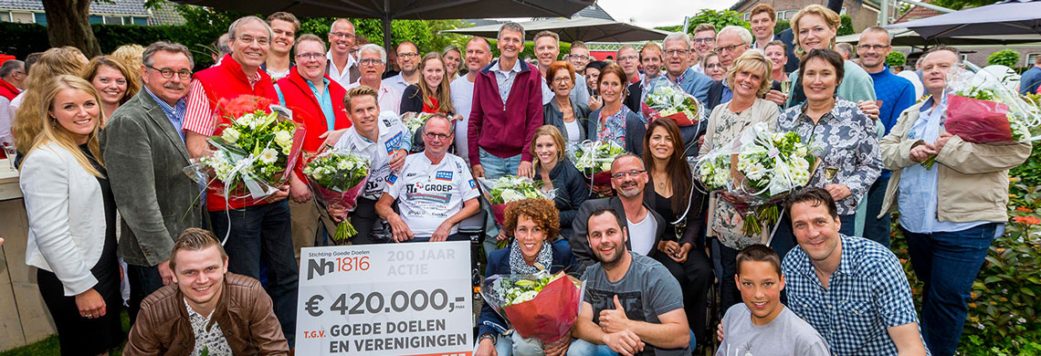 Groep mensen met boeketten bloemen en een cheque van 420.000 euro