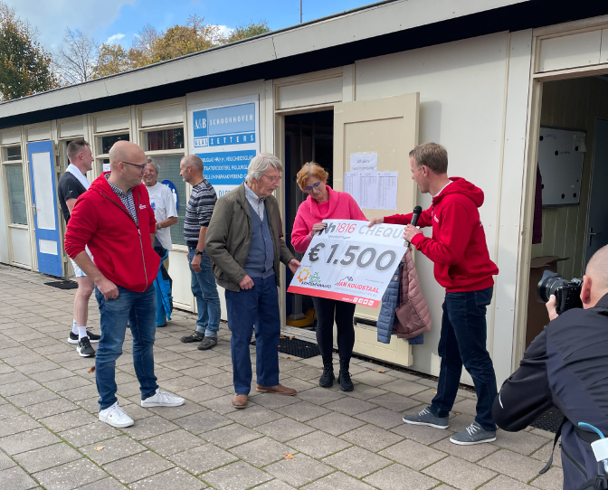 medewerker deelt cheque uit aan goed doel